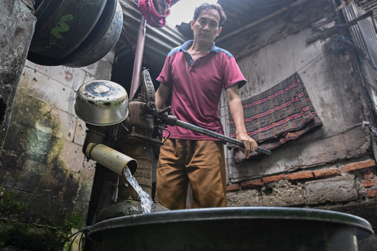 A man uses a manual pump to draw well water for bathing on Jan. 28, 2026, in Kemanggisan, Bekasi, West Jakarta.
