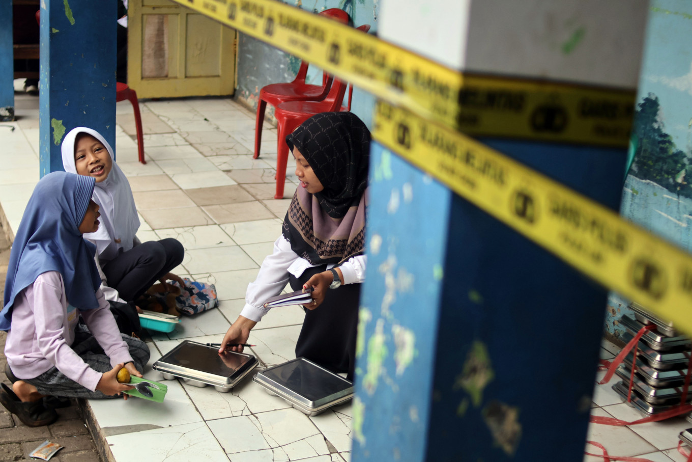 A teacher distributes free meals to students while schools remain closed following a building collapse at Madrasah Ibtidaiyah Miftahul Falah in Gunungputri, Bogor regency, West Java, on Feb. 2, 2026. The government has confirmed that the program will continue during Ramadan, with menus and distribution times adjusted for students observing the fast.