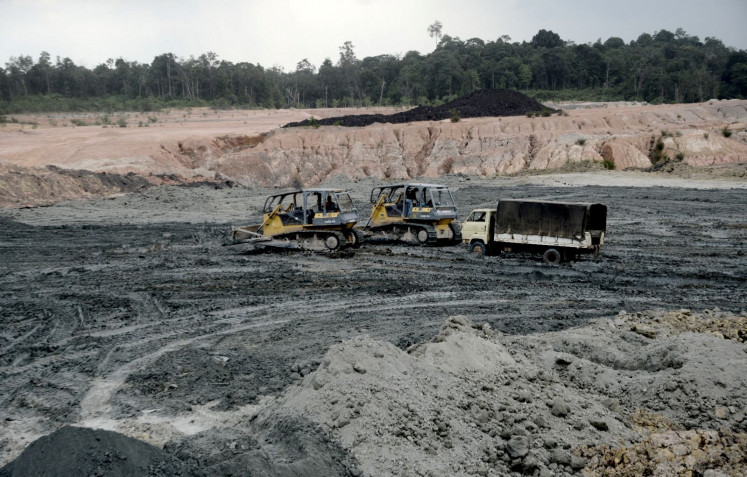 Heavy equipment operators work at an open-pit coal mine in Jambi on May 19, 2017.