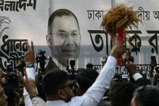 A poster of Bangladesh Nationalist Party (BNP) chairman and election candidate Tarique Rahman is displayed as supporters gather outside the party office in Dhaka on February 13, 2026. The Bangladesh Nationalist Party (BNP) celebrated a landslide victory on February 13 in the first elections held since a deadly 2024 uprising, with leader Tarique Rahman to become prime minister. 