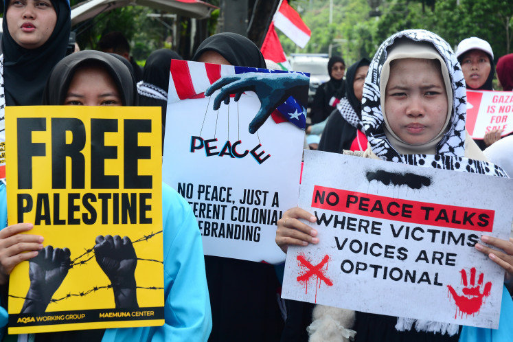 Woman holds a placard during a pro-Palestinian protest outside the Palestinian Embassy in Jakarta, Indonesia, Feb. 13, 2026. The protest was held against Israel and called on the Indonesian government to cancel the proposed multinational peacekeeping force for Gaza, following President Prabowo Subianto&rsquo;s invitation to Washington later this month for the first meeting of U.S. President Donald Trump&rsquo;s Board of Peace.