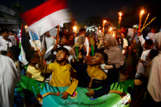 Children hold torches beneath the national flag at a gathering on Jl. Basuki Rachmat in East Jakarta on Feb. 14, 2026, before joining a traditional parade to welcome the holy month of Ramadan, which begins on Feb. 19 this year.