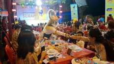 A man in Hanoman costume shakes hands with a visitor on Feb. 13, 2026, during the Tok Panjang communal dinner at the opening ceremony of Semawis Imlek night market in the Chinatown in Gang Gambiran, Semarang. Tok Panjang is usually held to celebrate Chinese New Year, locally known as Imlek, and this year will be the Year of the Horse.
