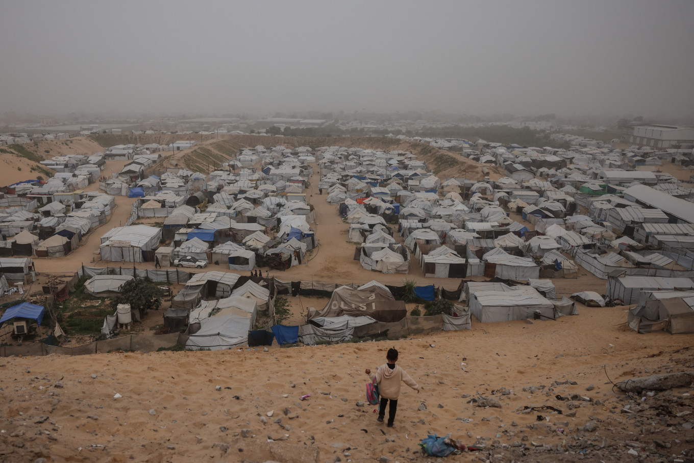 Desertified view: A child walks down a hill overlooking a camp for displaced Palestinians on Feb. 14 during hazy, dusty weather in Khan Yunis in the southern Gaza Strip.