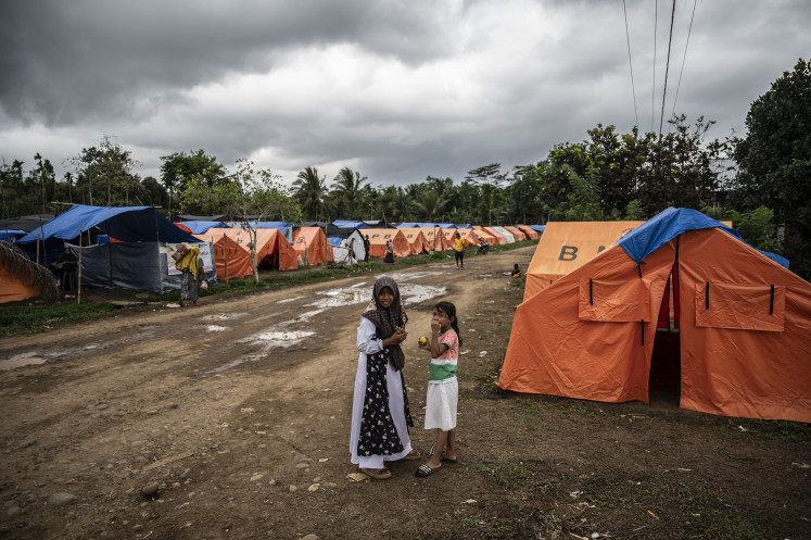 Interrupted childhood: Two children from Gampong Gunci village stand in a temporary housing complex on Monday in Sawang, North Aceh, Aceh province. A total of 326 residents from 85 families have been living in the emergency shelters for three months after flash floods and landslides struck their villages in late November 2025. They are scheduled to relocate to temporary housing at the start of Ramadan.