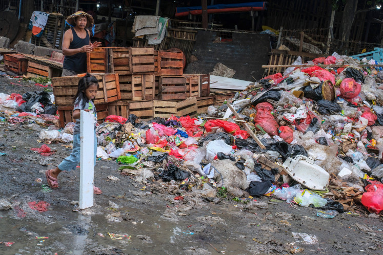 A child carries an item scavenged from a pile of trash on Jan. 20 on a public road in Pasar Minggu, Jakarta. Garbage-choked streets, overloaded landfills and fear of trash avalanches haunt greater Jakarta, as the world's most populous metropolis grapples with a waste crisis.