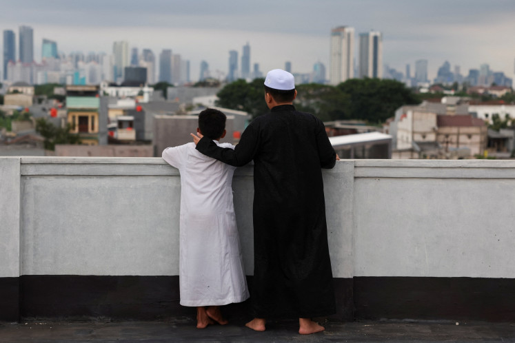 Muslim boys gather to watch the position of the moon to determine the start of the holy fasting month of Ramadan, on the roof of Al-Musyari'in mosque in Jakarta, Indonesia, February 17, 2026.