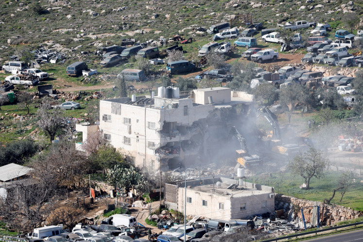 Heavy machinery demolishes a Palestinian building on Feb 18, 2026, near Hebron in the Israeli-occupied West Bank.