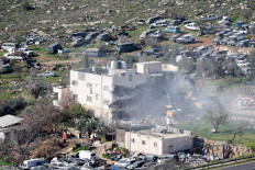 Heavy machinery demolishes a Palestinian building on Feb 18, 2026, near Hebron in the Israeli-occupied West Bank.