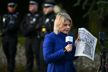 A journalist reports from the scene while holding a newspaper with an image of Britain's former prince Andrew at an entrance to Wood Farm on the royal family's Sandringham Estate in Norfolk, eastern England on Feb. 20, 2026, a day after Andrew Mountbatten-Windsor was arrested. Britain's royal family was thrown into crisis on Feb. 19 after former prince Andrew was arrested by police and held for hours in a blow to the monarchy unprecedented in modern British history.