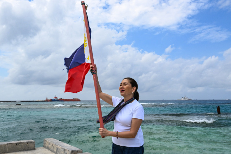 Philippine senator Risa Hontiveros raises the national flag on Feb. 21, 2026, on Thitu Island in the South China Sea.