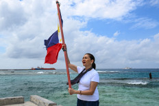 Philippine senator Risa Hontiveros raises the national flag on Feb. 21, 2026, on Thitu Island in the South China Sea.