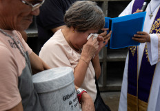 A relative of one of the victims of extrajudicial killings of former Philippine president Rodrigo Duterteʼs drug war cries next to the urn of her son on Feb. 20 during the inurnment rites at the Shrine of Healing (Dambana ng Paghilom) at a cemetery in Caloocan, Metro Manila.