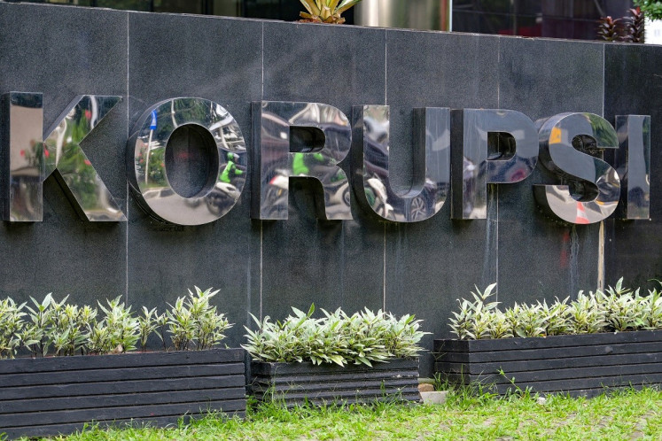 The reflection of motorists is seen in the Corruption Eradication Commission (KPK) building sign, in Jakarta, on June 27, 2023. 