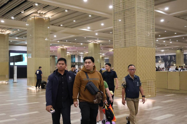 Police officers escort human trafficking suspect Rifaldo Aquino Pontoh (second left) after being arrested at I Gusti Ngurah Rai International Airport in Badung regency, Bali, on Feb. 21, 2025. Rifaldo allegedly used social media accounts to advertise vacancies and promised high salaries in Cambodia to job seekers.