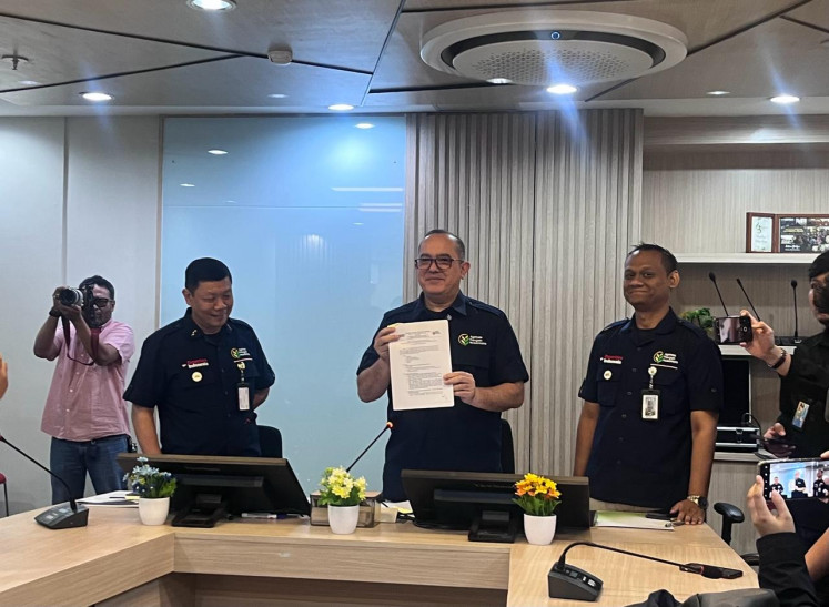 State-owned agriculture firm PT Agrinas Pangan Nusantara president director Joao Angelo De Sousa Mota (center) poses for a picture in a press conference on Feb. 24 while showing a document related to the decision to import 105,000 vehicles from Indian firms Tata Motors and Mahindra.