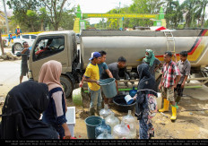 People fill buckets, empty gallon bottles and other containers with clean water from a water truck on Feb. 25 in Kuala Simpang, a city Aceh Tamiang regency, Aceh, which was affected by the Sumatra floods and landslides in November 2025.