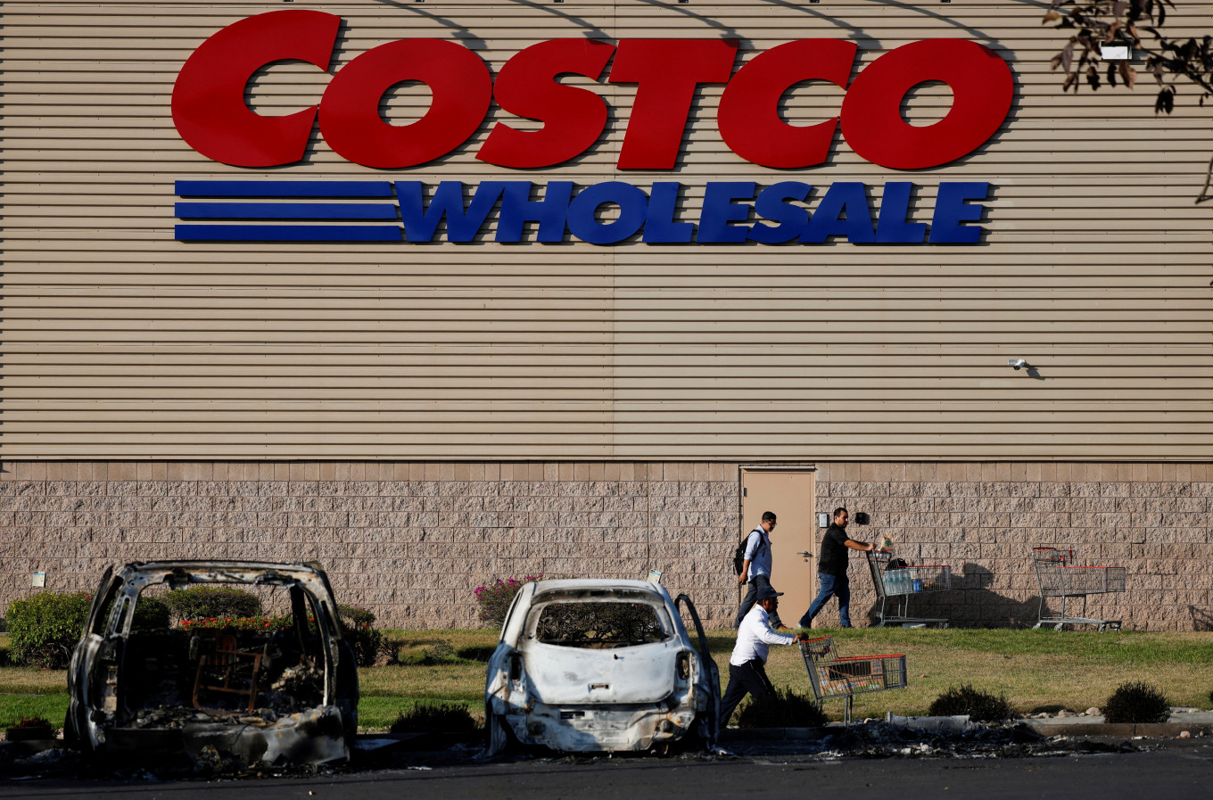 People push shopping carts in the parking lot of a supermarket on Feb. 24 where several vehicles were consumed by flames days after a series of blockades and attacks by organized crime following a military operation in which drug cartel leader Nemesio Oseguera, known as &ldquo;El Mencho,&ldquo; was killed, in Puerto Vallarta, Mexico.
