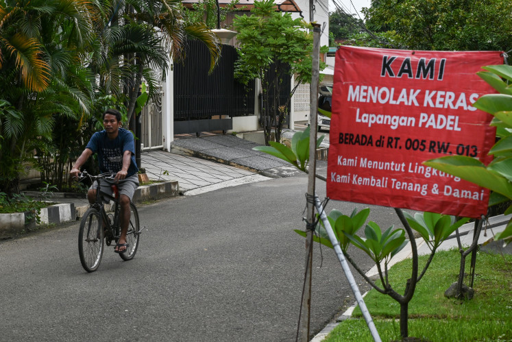 Game off: A cyclist rides on Tuesday, Feb. 24, 2026 past a banner opposing the construction of a padel court in Pulomas, Pulo Gadung, East Jakarta. Residents say they put up the banner in protest because they were never consulted about the construction by the management and fear noise and disruption in their neighborhood.