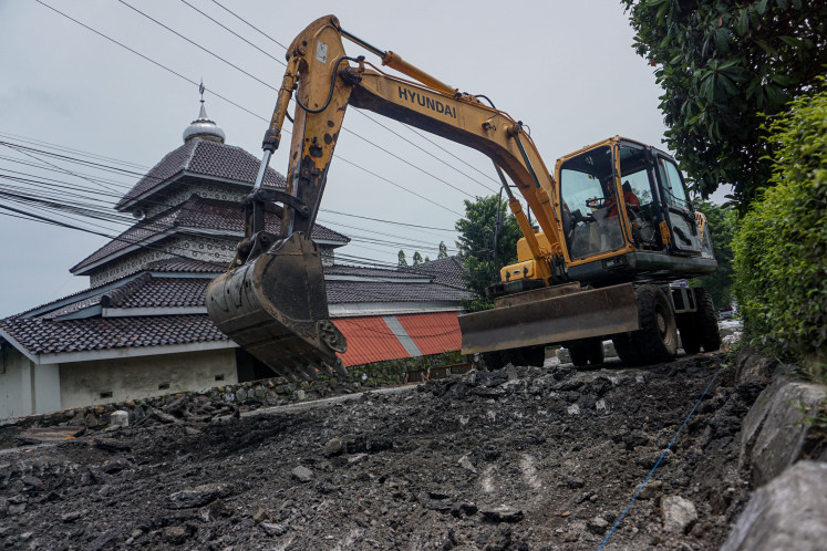 Workers operate heavy equipment on Feb. 2 to remove damaged asphalt for repairs on a section of the Java Northern Highway in Pekalongan, Central Java.