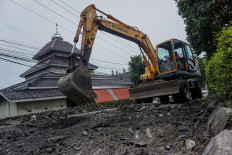 Workers operate heavy equipment on Feb. 2 to remove damaged asphalt for repairs on a section of the Java Northern Highway in Pekalongan, Central Java.