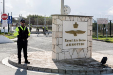 Police officers stand guard at the gates of the Royal Air Force Akrotiri base, a British overseas territory near the Cypriot coastal city of Limassol, as peace protesters rally against its alleged use to supply Israel's war in Gaza, a claim denied by Britain, on January 14, 2024. 