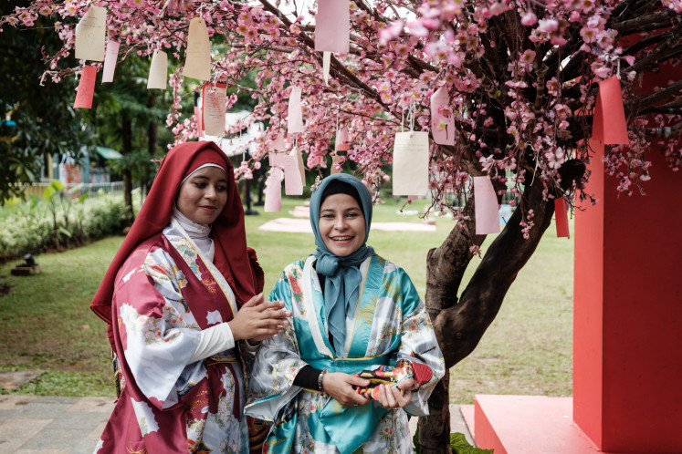 Indonesian women dressed in Japanese kimono style clothes pose under artificial cherry blossoms during the Japanese Summer Festival at Taman Mini Indonesia Indah, a cultural park, in Jakarta on July 7, 2024. 