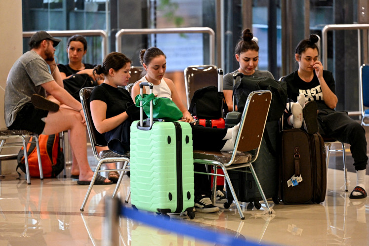 Passengers wait amid flights disruptions as a result of the Israeli-US strikes on Iran, at Ngurah Rai International Airport in Bali, on March 2, 2026. 