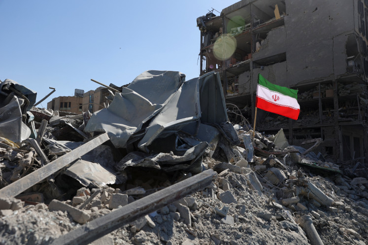 The national flag of Iran flies in the wind as debris lies scattered in the aftermath of an Israeli and United States strike on a police station, amid the US-Israeli conflict with Iran, in Tehran on March 4, 2026.