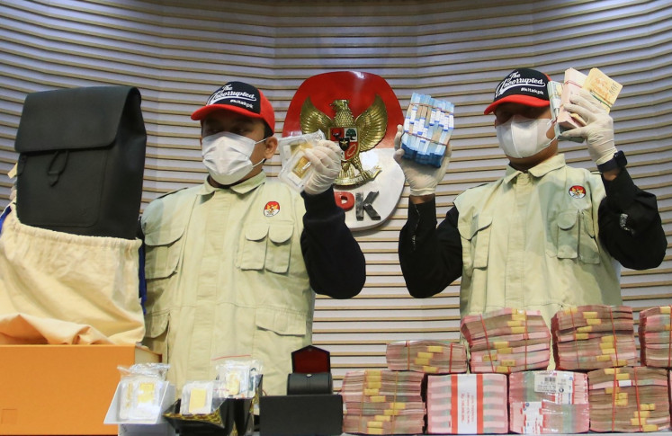 Corruption Eradication Commission (KPK) investigators hold up cash and gold bars on Feb. 5, 2026, seized during the arrest of Finance Ministry's customs and excise directorate general officials at a press briefing at the antigraft body headquarters in Jakarta. 