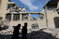 Two people walk past damaged buildings on March 4, 2026, following a strike on a police station in Tehran, amid the United States-Israeli war with Iran. 