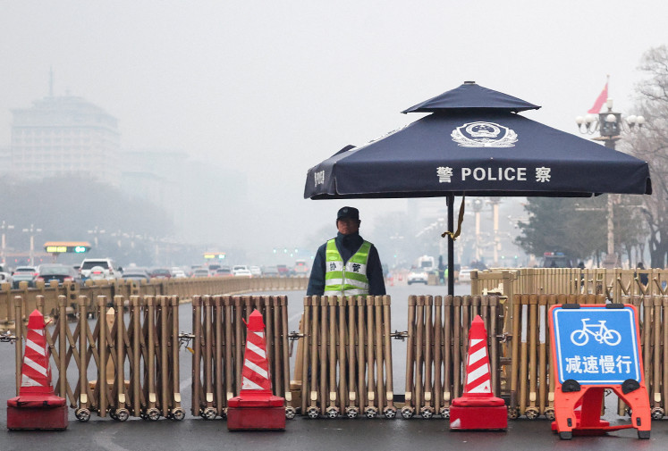 A police officer stands guard at a checkpoint at Changan Avenue on a foggy day ahead of the annual meeting of the National People's Congress in Beijing on March 2, 2026.