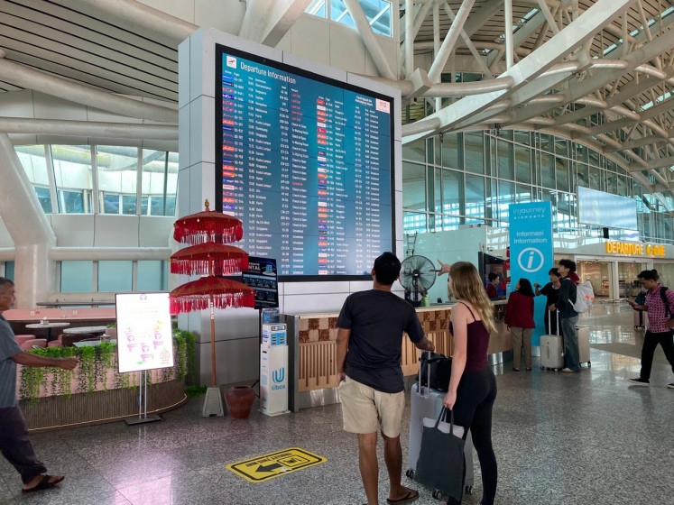 Two travelers look at a flight information display at I Gusti Ngurah Rai International Airport in Denpasar, Bali, in this undated handout photo.
