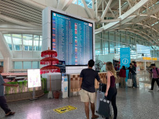 Two travelers look at a flight information display at I Gusti Ngurah Rai International Airport in Denpasar, Bali, in this undated handout photo.
