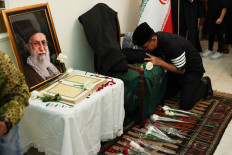A man pays his respects to the late Iranian supreme leader Ayatollah Ali Khamenei (left, in framed picture) on March 5, 2026, during a prayer service at the Iranian ambassador's residence in Menteng, Central Jakarta.