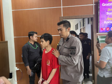 Fandi Ramadhan (second left) is escorted on March 5, 2026, with his hands handcuffed by a guard after receiving a five-year jail term for smuggling drugs, in Batam, Riau Islands. Fandi's case went viral after prosecutors demanded the death penalty for Fandi and five other defendants.