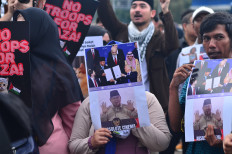 A protester holds a poster on March 6, 2026, during a demonstration against the Board of Peace (BoP) outside the Senayan Legislative Complex, Central Jakarta. An alliance of students and civil society groups demonstrated against the United States and Israel strikes on Iran, saying they violate international law and global peace, and urged the government to review Indonesia&rsquo;s agreement in the BoP since it does not align with the United Nations Security Council mandate.