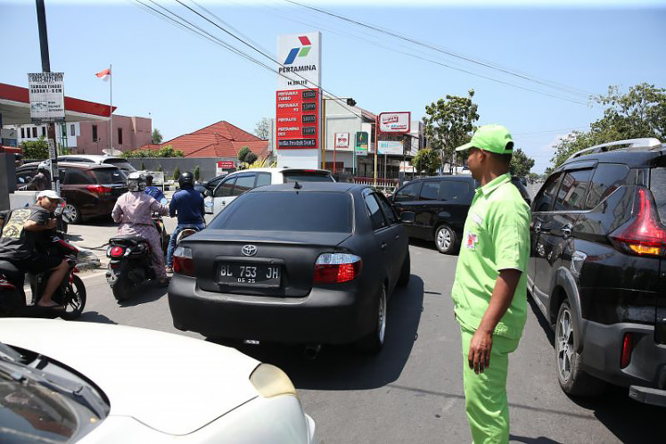 An employee directs motorists lining up to buy fuel at a gas station in Banda Aceh on March 5, 2026.