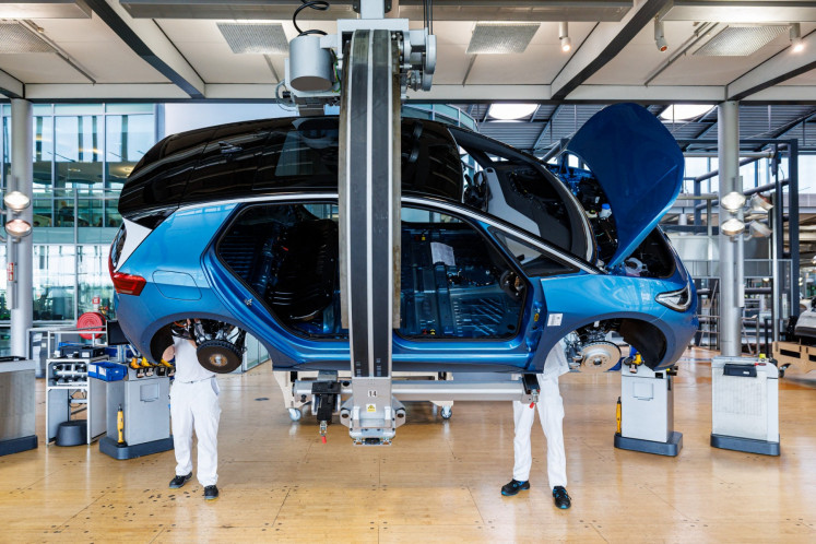 Employees work on the assembly line for the ID.3 electric car of German carmaker Volkswagen, at the 'Glaeserne Manufaktur ( Transparent Factory) production site in Dresden, eastern Germany, on May 14, 2025.