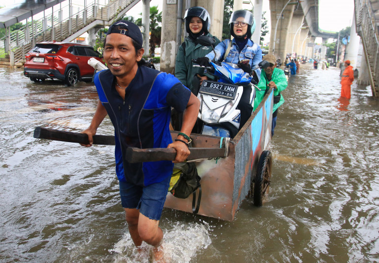 A motorcyclist uses a pedicab service on March 8, 2026, to cross floodwaters on Jl. Ciledug Raya in Ulujami, South Jakarta. The flooding had been caused by overflow of the Pesanggrahan and Keuangan rivers after heavy rains hit the Greater Jakarta area.
