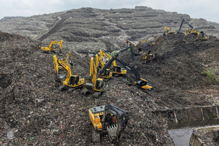 Desperate search: A rescue team uses heavy machinery to search for people on March 9  following a landslide at Bantargebang landfill in Bekasi, West Java. A landslide at the country&rsquo;s biggest landfill buried trucks and food stalls, killing four people, rescuers said on March 9 as they searched for at least five more reported missing.
