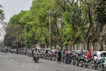 People wait in a queue to refuel their vehicles near a fuel station in Dhaka on March 8, 2026. 
