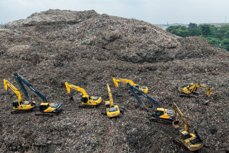 This aerial picture shows a rescue team using heavy machinery to search for people following a landslide at Bantar Gebang landfill in Bekasi, West Java, on March 9, 2026. A landslide at the country's biggest landfill buried trucks and food stalls, killing four people, rescuers said on March 9 as they searched for at least five more reported missing.