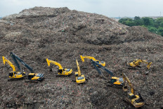 This aerial picture shows a rescue team using heavy machinery to search for people following a landslide at Bantar Gebang landfill in Bekasi, West Java, on March 9, 2026. A landslide at the country's biggest landfill buried trucks and food stalls, killing four people, rescuers said on March 9 as they searched for at least five more reported missing.