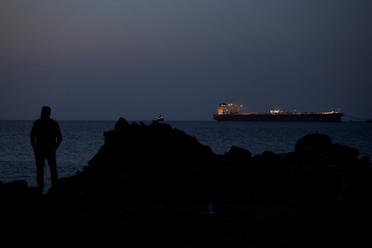 A man looks out toward the crude oil tanker Parnassos anchored in the Strait of Hormuz off Omani capital Muscat on March 10, 2026, amid the United States-Israeli war with Iran.