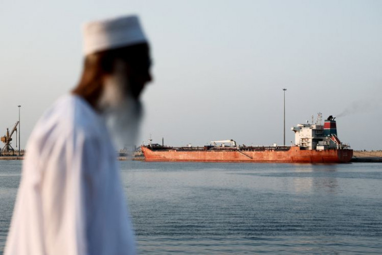 A man stands onshore against the backdrop of the Callisto tanker on March 12, 2026, anchored at Sultan Qaboos Port in Muscat amid a sharp drop in maritime traffic in the Strait of Hormuz due to the United States-Israeli war with Iran.