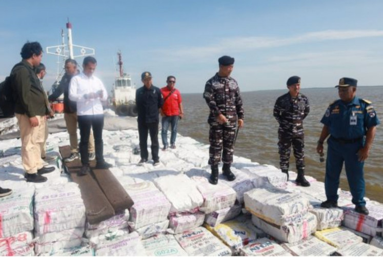 Representatives from various agencies stand on top of sacks of illegal mangrove charcoal on March 5 on board KLM Samudera Indah Jaya GT 172 at Dumai Naval Base pier in Dumai city, Riau. An Indonesian Navy joint team impounded the ship during an anti-smuggling operation on March 5 in the waters of Meranti Islands regency. 