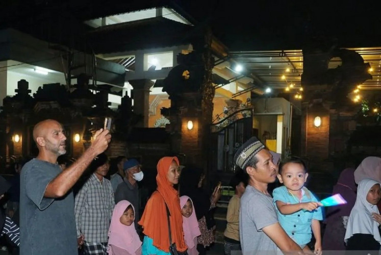 Using his mobile phone, a tourist records a takbiran Islamic procession in Canggu Permai, Badung regency, in the predominantly Hindu island of Bali on June 5, 2025.