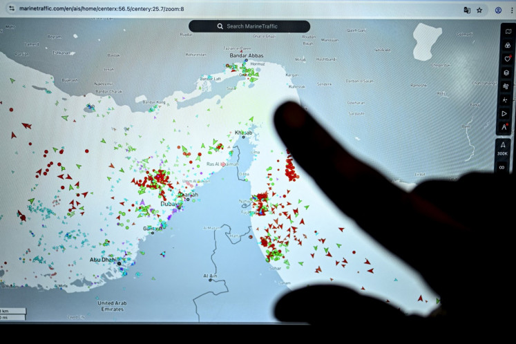 A person points at a page on the Marinetraffic website that shows commercial shipping traffic on the edge of the Strait of Hormuz near the Iranian coast, on March 4 in Paris. 