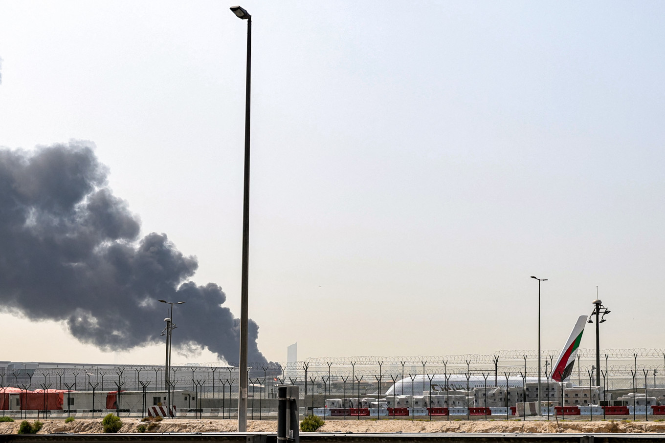 A smoke plume rises from an ongoing fire on Monday near Dubai International Airport in Dubai, the United Arab Emirates. Flights were gradually resuming at Dubai airport on Monday, previously the world's busiest for international flights, the airport operator said, after a drone-related incident sparked a fuel tank fire nearby, as Iran kept up its Gulf attacks.